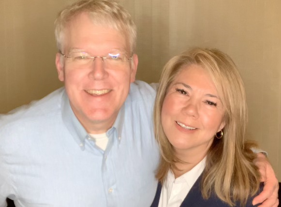Man and woman for a photo in front of a wall